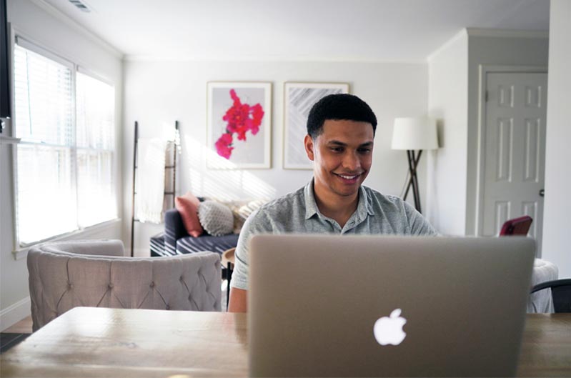 person in a living room smiling and looking at a laptop