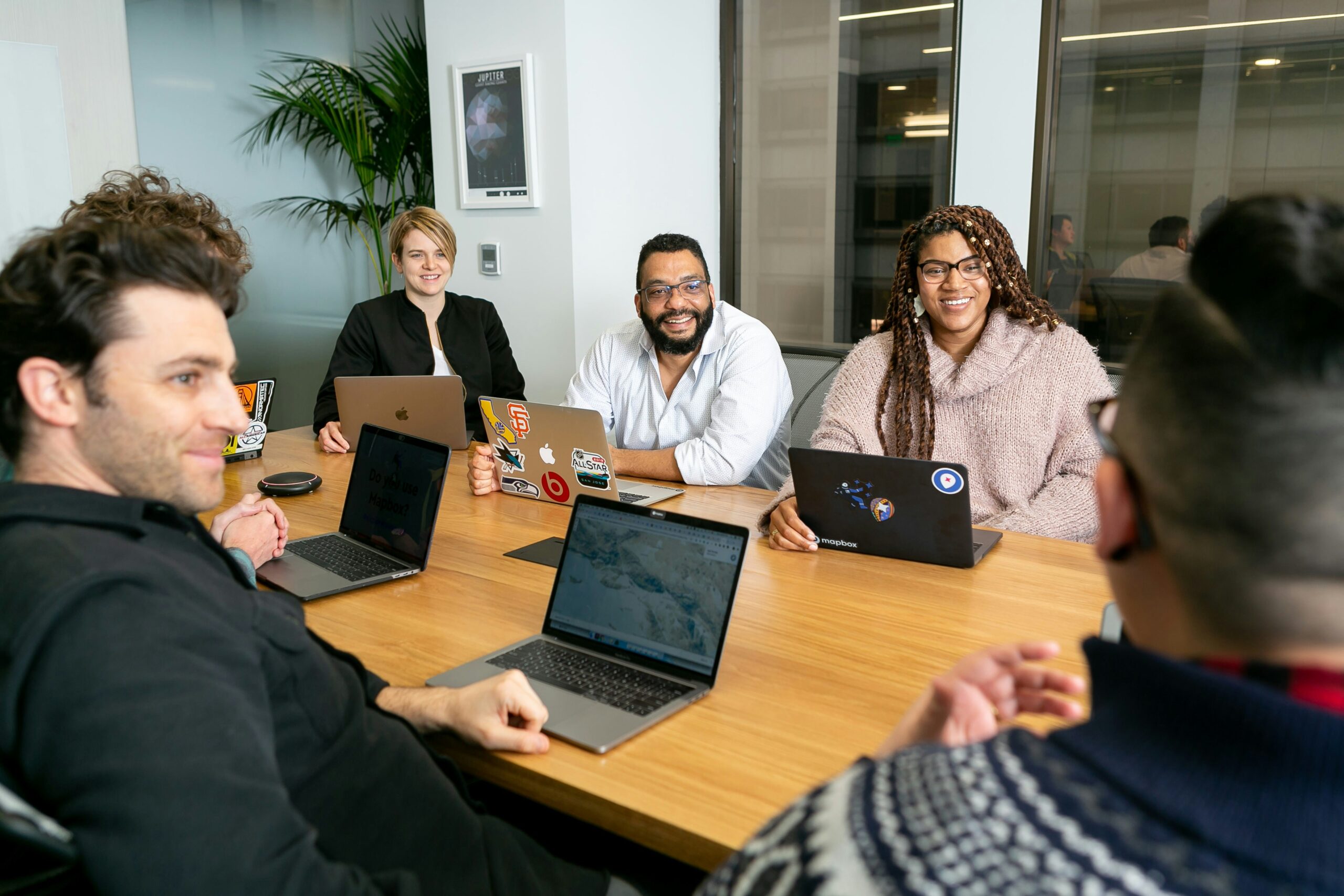 mapbox-ZT5v0puBjZI-unsplash group of people around a conference table with laptops