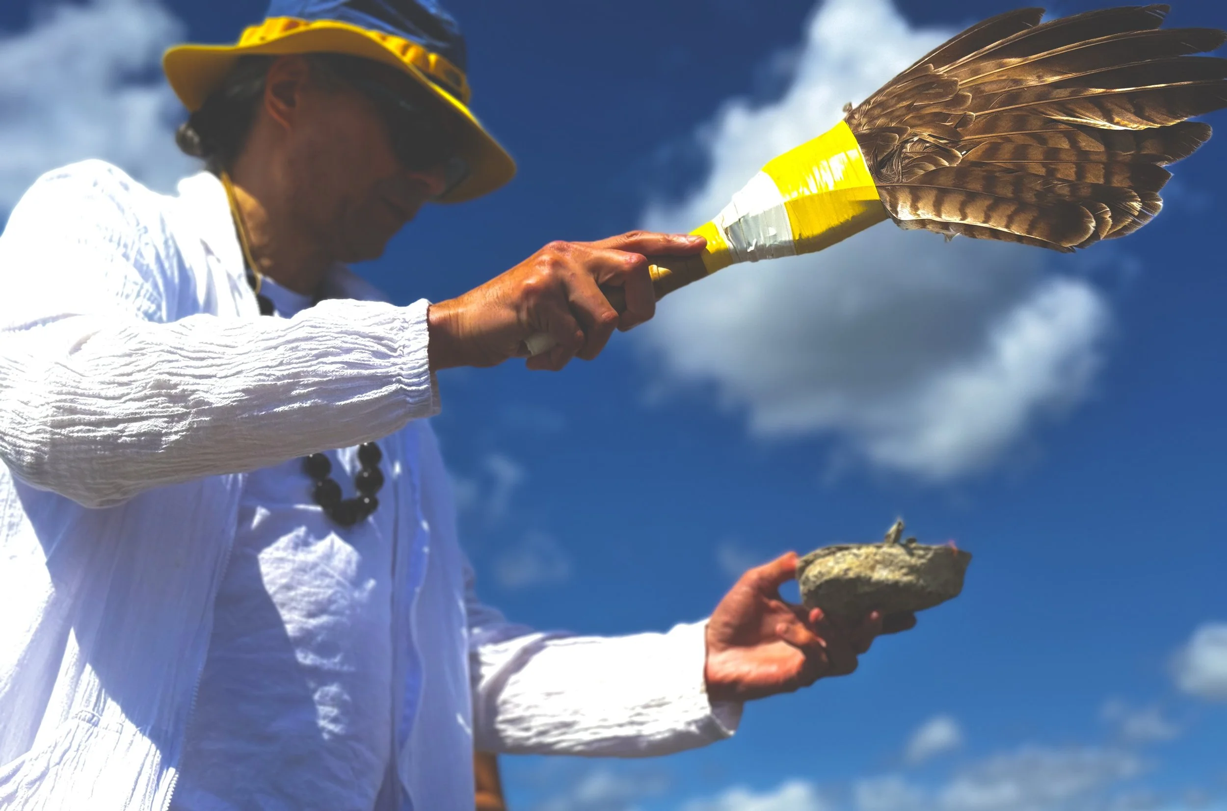 OCC Blog Post Image Participant uses a feather fan and shell during an outdoor cultural blessing ceremony